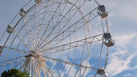 A large ferris wheel turns slowly against a backdrop of blue sky and clouds. Vidéo 344527967