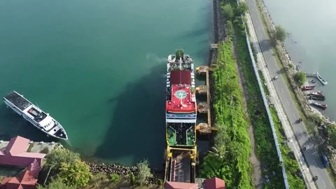 A large ferry docks at a port while a smaller passenger boat waits nearby 库存影片 319518234