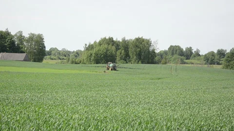 Large field crop rides tractor with sprinklers corn pests Stock Footage 38395592