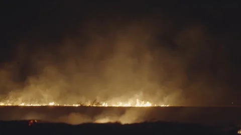 Large fire is burning in the distance, with smoke billowing into the sky poll Stock Footage 277911189
