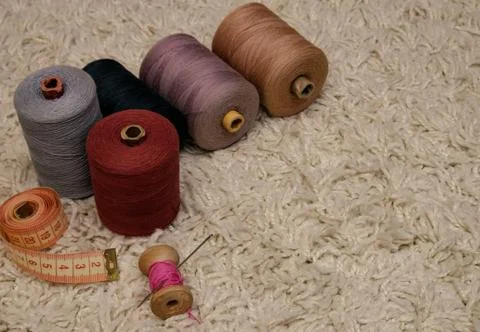 Large five spools of thread, meter, spool of pink thread with a needle lie on Stock Photos