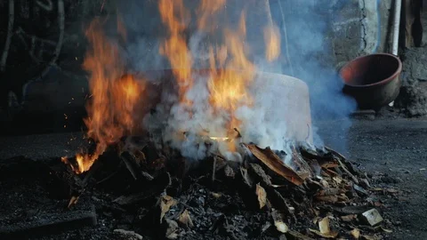 Large flames heating up a copper pot over a wooden blast furnace Stock Footage 98843620