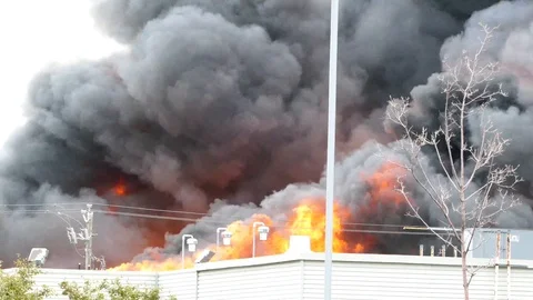 Large flames ripping on top of a building and creating thick dense smoke Stock Footage 97686049