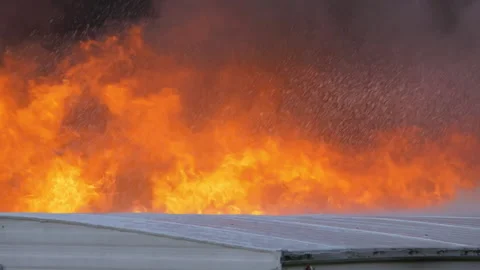 Large flames rising from behind a wall with water falling from out of frame Stock Footage 229816893