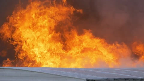 Large flames rising from a large building fire. Slow motion footage of a massive Stock Footage 229816640
