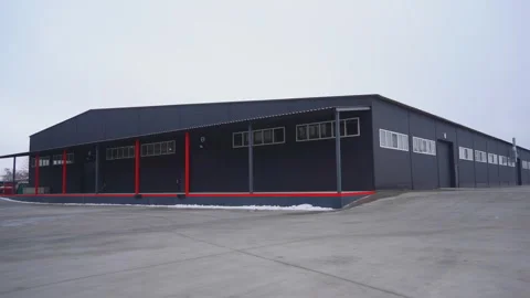 Large flat roofed black storehouse building with empty ramp Stock Footage 304394575