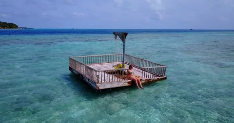 A large floating dock with a yellow hanging chair and young woman floating Stock Footage 118156445