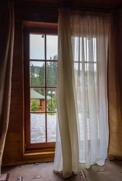 Large floor to ceiling partly curtained wooden window, inside view Stock Photos