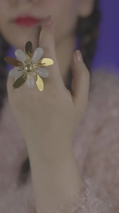 Large flower-shaped ring worn on a womans finger, with white and gold metallic Video stock 307062686