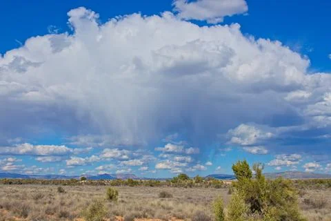 Large fluffy cloud in a blue sky over the desert. Stock Photos