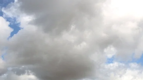 Large fluffy clouds slowly float across the blue sky Stock Footage 106353682