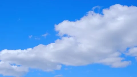 Large fluffy white cloud and wispy band of clouds against a bright blue sky Stock Footage 343735442