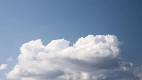Large fluffy white cumulus clouds float calmly in bright clear blue sky dur.. Stockfoto's