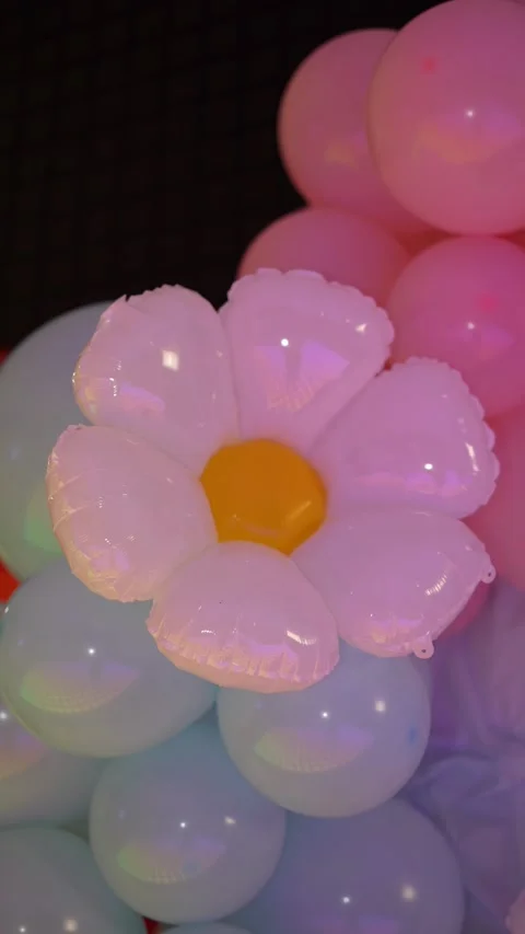 A large foil daisy balloon integrated into a pastel balloon arch Stock Footage 340513331