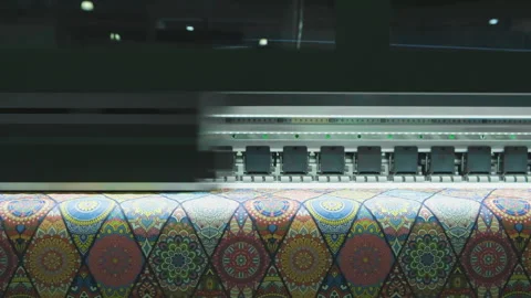 Large-format printer moves across colorful patterned fabric. Print head advan Stock Footage 331854412