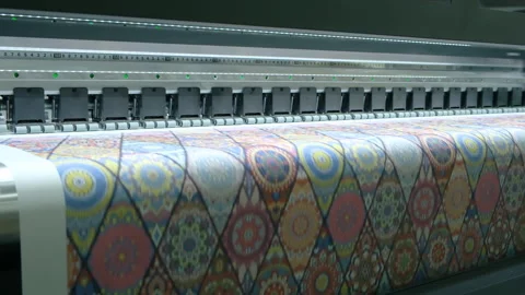 Large-format printer moves across colorful patterned fabric. Print head advan Stock Footage 331863360