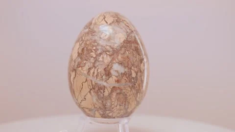 Large fragmented Granite egg rotating slowly on a turntable in front of a Video stock 269117665