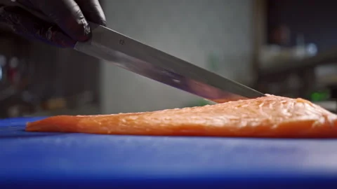 Large frame of men's hands that easily cut fragrant and fresh red fish to make Stock-Footage 165777685