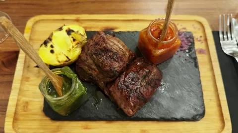 Large fresh delicious beef steak with various sausages and potatoes on a wooden Stock Footage 297778696