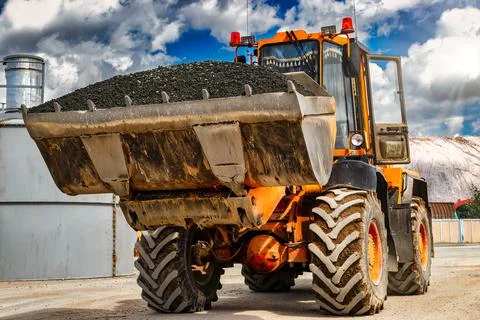 A large front loader transports crushed stone or gravel in a bucket at a cons 스톡 사진