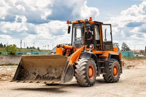 A large front loader transports crushed stone or gravel in a bucket at a cons Stock Photos