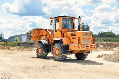 A large front loader transports crushed stone or gravel in a bucket at a cons Photos
