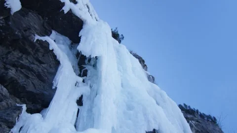 Large frozen waterfall on a mountain cliff, in the Alps, Switzerland Stock Footage 240147762
