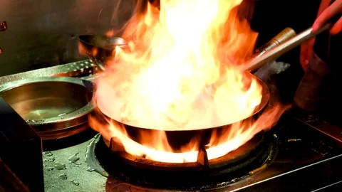 In a large frying pan cook prepares Udon on fire Stock Footage 113560198