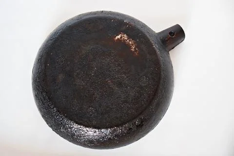 A large frying pan without a handle, with a burnt bottom on a white backgro.. Stock Photos