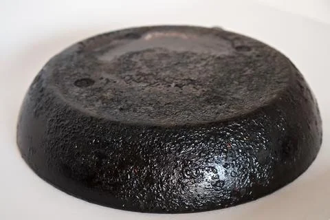 A large frying pan without a handle, with a burnt bottom on a white backgroun Stock Photos