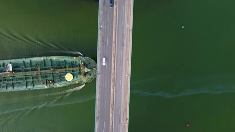 Large general cargo ship tanker bulk carrier passing under a bridge with heavy Stock Footage 196986281