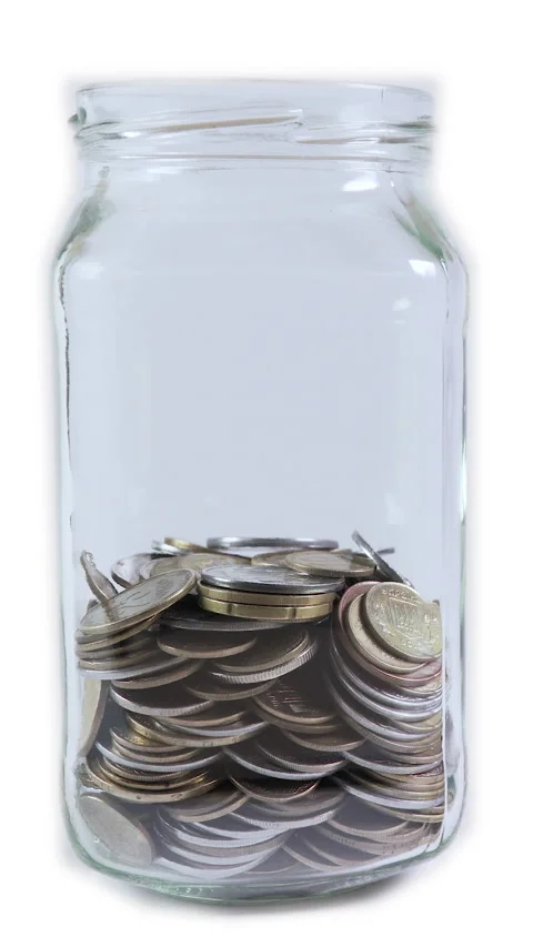 Large glass jar filled with various coins, on white background. Stock Footage 288319112