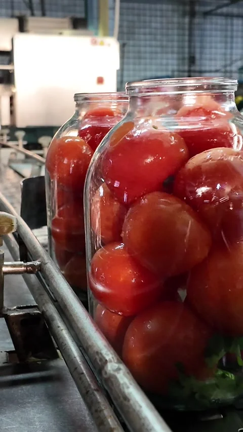 Large glass jars full of ripe tomatoes moving on conveyor Stock-Footage 348251069