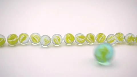 Large glass marble striking small swirl marbles on white background Stock Footage 308866005