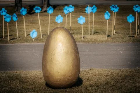 A large gold-painted Easter egg sculpture standing. Fotos de archivo