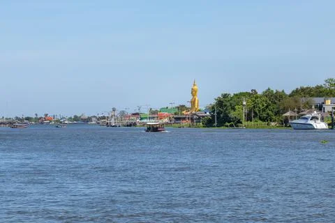 A large golden Buddha image sits along the Chao Phraya River at Wat Bang Chak Stock Photos
