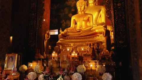 Large golden Buddha statues inside temple with candles and devotional altar Stock Footage 331483862