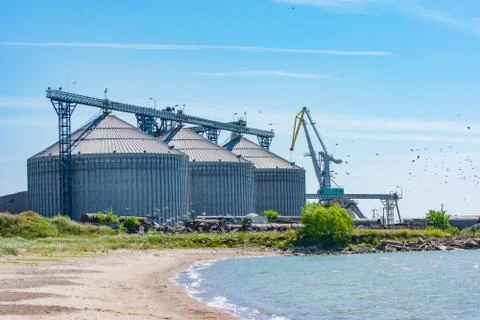 Large grain elevator silos in port with flying birds and sea coast (Port of L Stock Photos