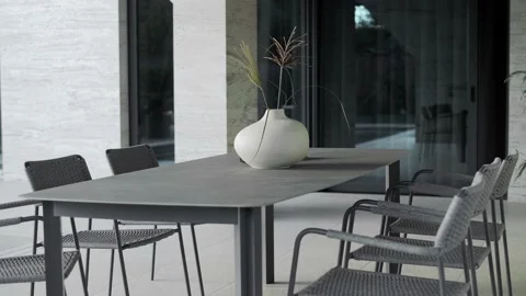 Large granite table with lots of wicker chairs for the exterior of a villa Stock Footage 220774024