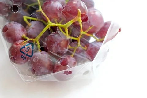 Large grapes in labeled packaging. On a light background Stock Photos