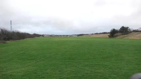 Large grassed area with tyre tracks houses in distance 動画素材 260504326