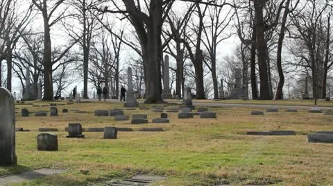 Large  graveyard in the middle of several trees with people walking through it Stock Footage 10577949