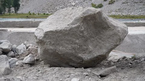 Large gray boulder sitting on a construction site with dirt and debris. Stock Photos