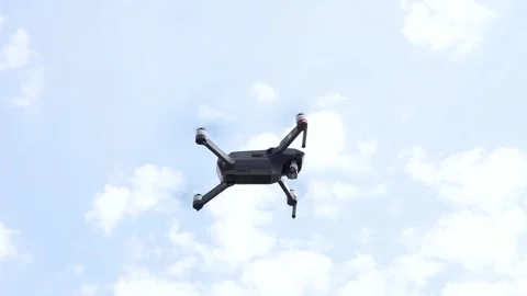 A large gray drone hovered above the ground against a cloudy sky. Stock Footage 134415879