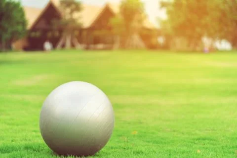 Large gray rubber balls placed on green grass in the public park. Stock Photos