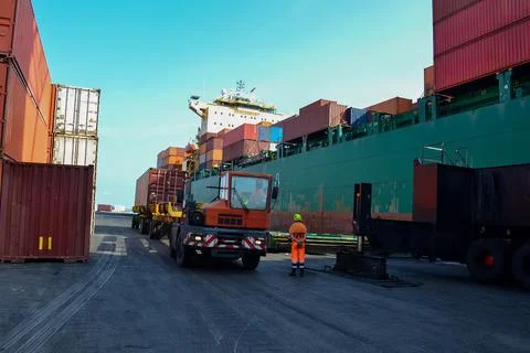 Large Green Cargo Ship Docked at a Busy Shipping Port with Worker Nearby Stock Photos