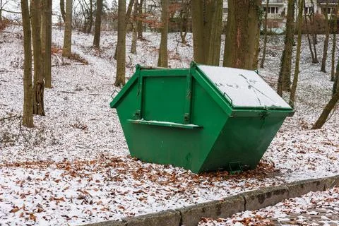 A large green garbage container against the background of trees in a snow-c.. Stock Photos