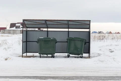 Large green garbage containers in winter under a canopy Stock Photos