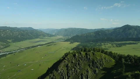 Large green meadows and high green mountains against the blue sky. Aerial Stock Footage 165968673