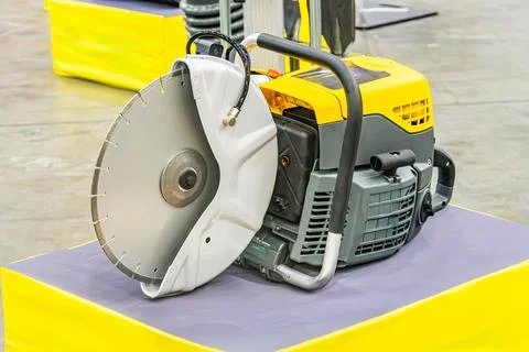 A large grey industrial drill, placed on a flat surface against a yellow back Stockfoto's
